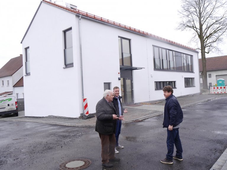 Bürgermeister Manfred Krä, Bauamtsmitarbeiter Julian Mauerer und Architekt Hans Oswald vor dem fast fertigen Bürgerhaus
