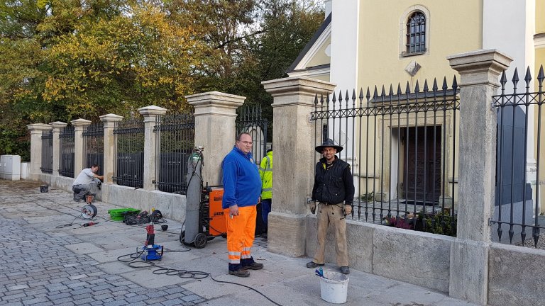Hausmeister Manfred Paukner und Steinmetz Matthias Gebel bei der Sanierung des historischen Friedhofzauns